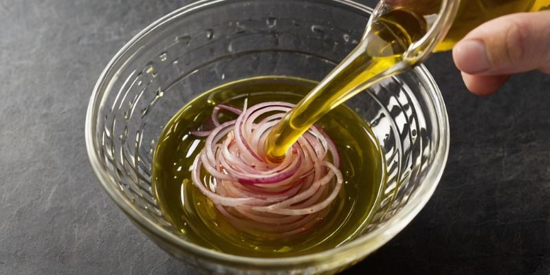 A freshly prepared vinaigrette with minced shallots being whisked in a glass bowl