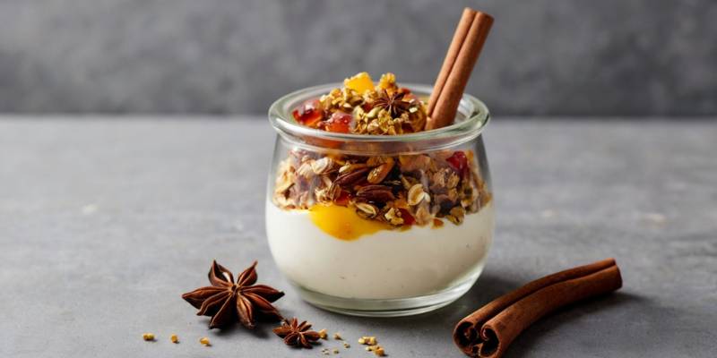 A healthy yogurt parfait topped with dried star anise powder, surrounded by cinnamon sticks and honey